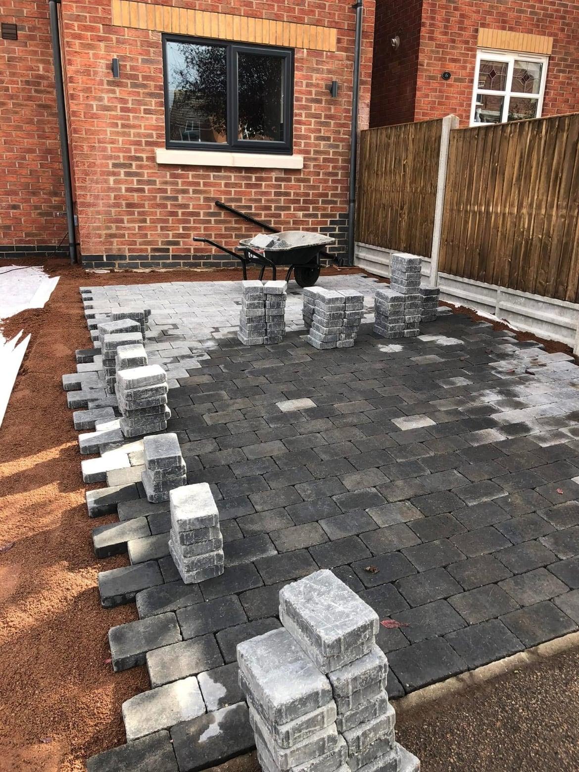 Grey block paving partly laid on a driveway with packs of blocks ready to go