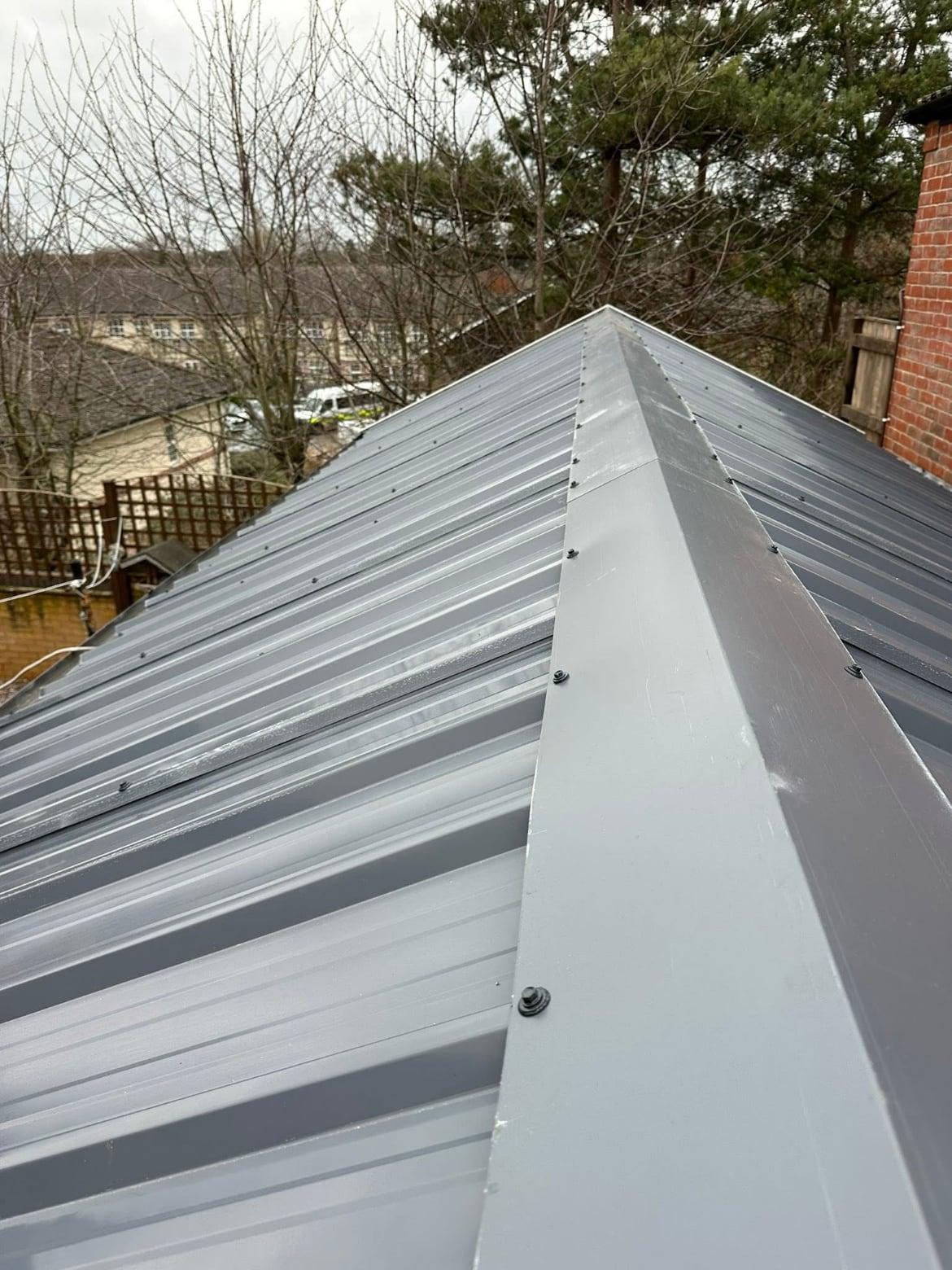Garage roof re-covered with grey profiled metal sheeting and a ridge cap