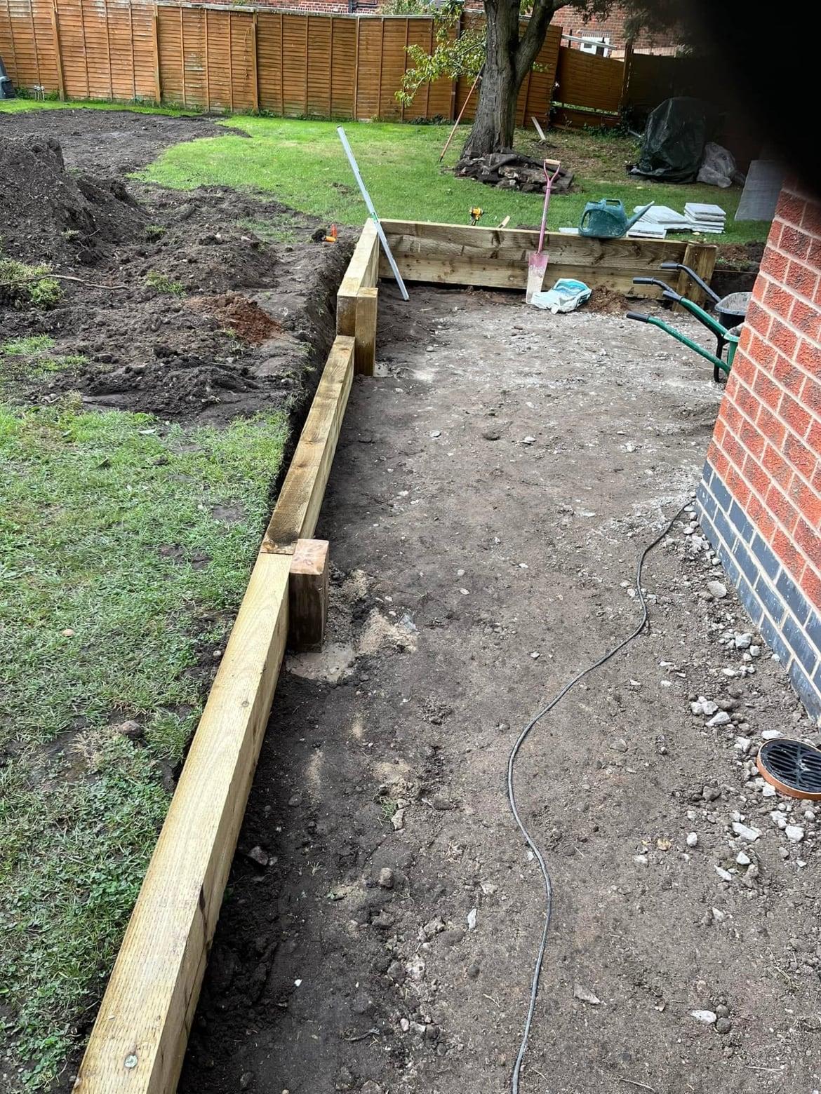 Timber sleeper edging being installed along a prepared path beside a lawn