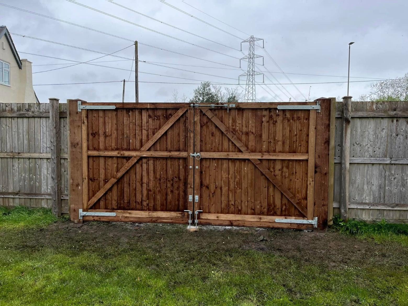 Ledged and braced timber double gates set into a fence line beside a field
